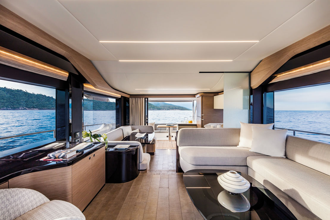 The salon, with an L-shaped sofa, dining table beyond and full-height glazing down both sides.