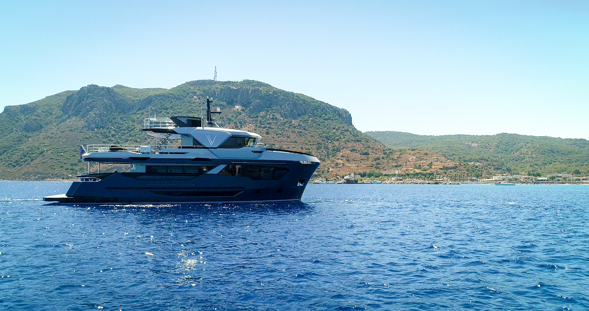 M/Y V at anchor beneath a headland