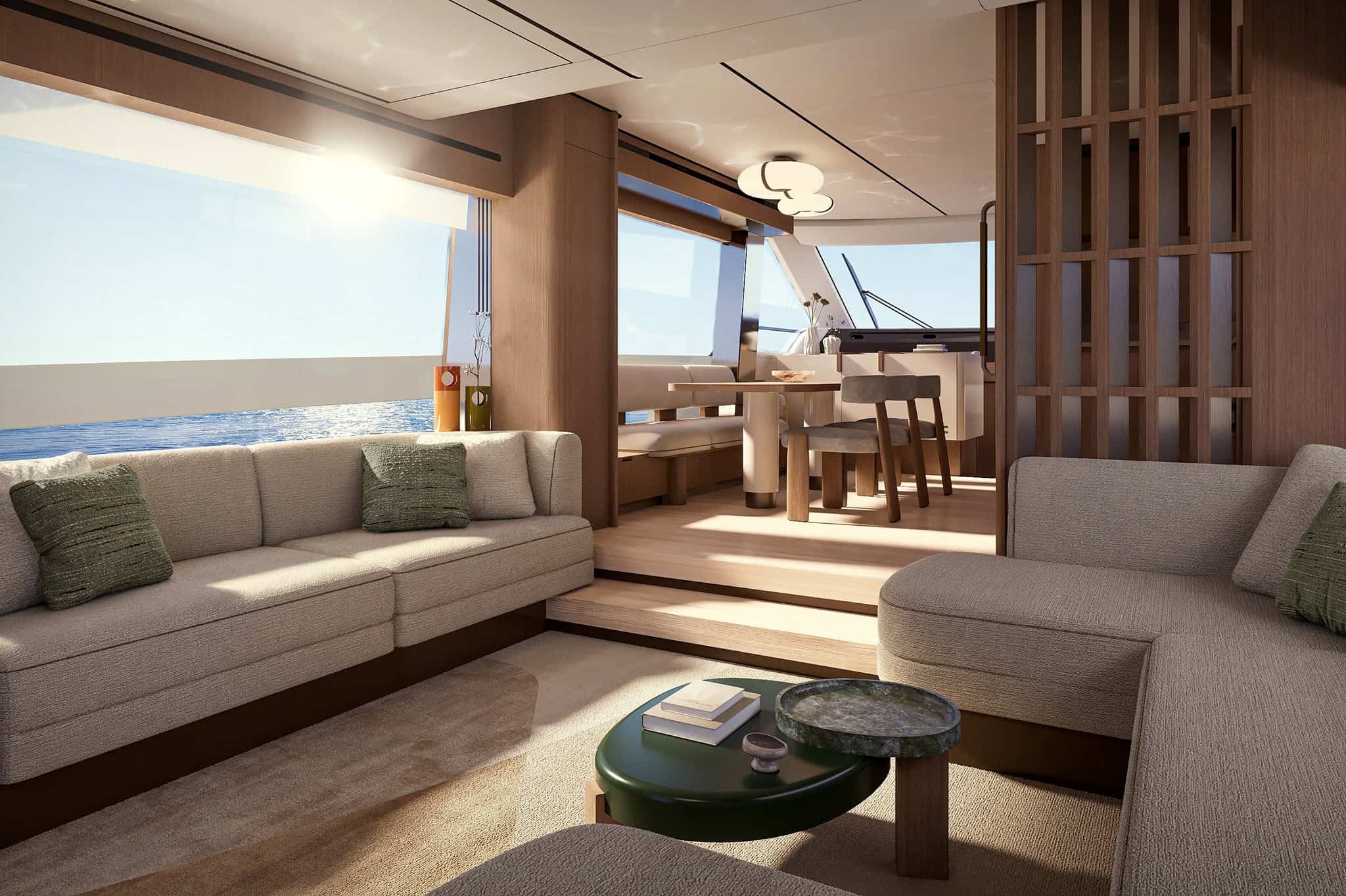 The saloon from the aft doorway, sofas to both sides in pale bouclé with green cushions, a low green table, and the dining table and helm framed by a slatted screen