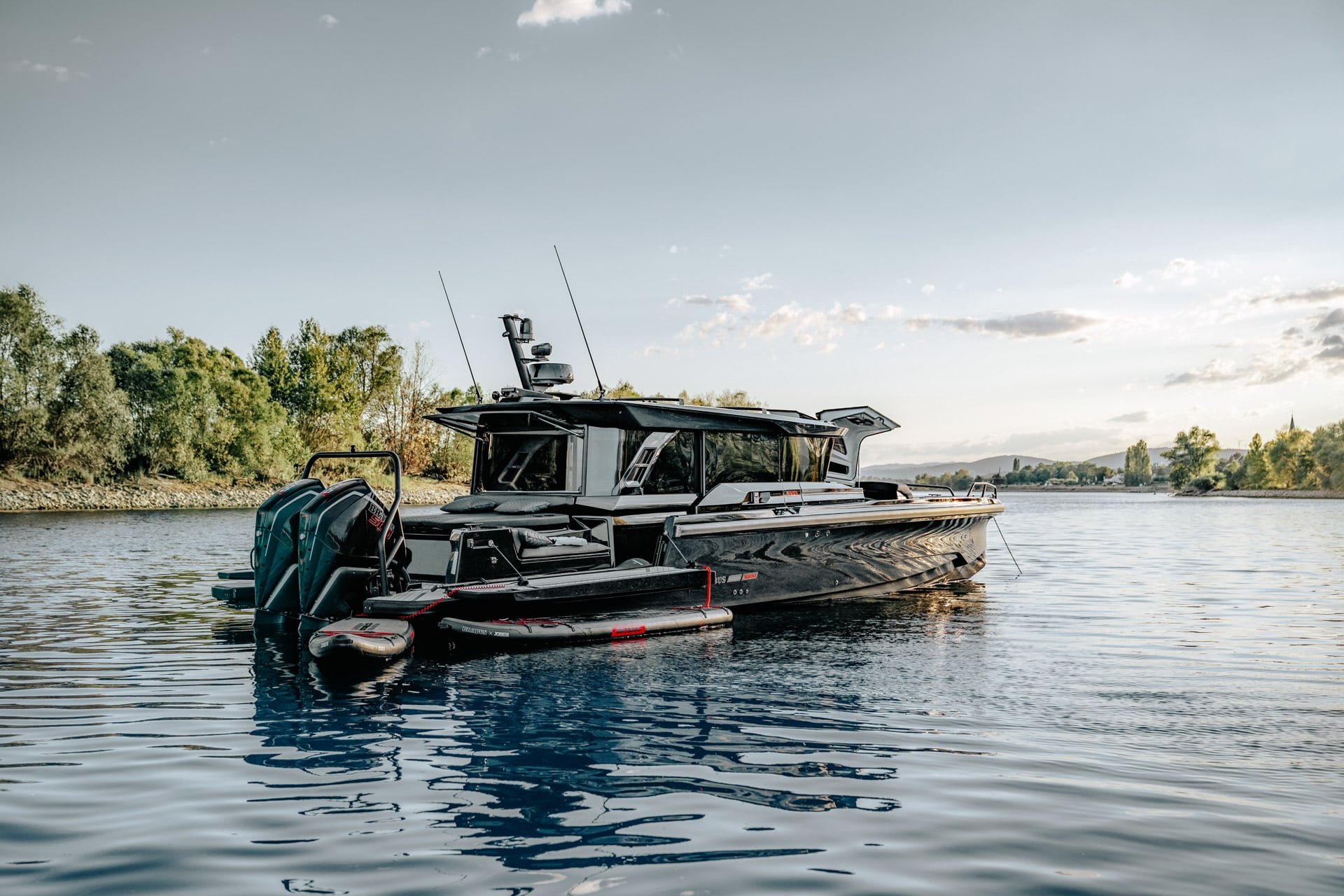The boat lying still on a river with trees behind it