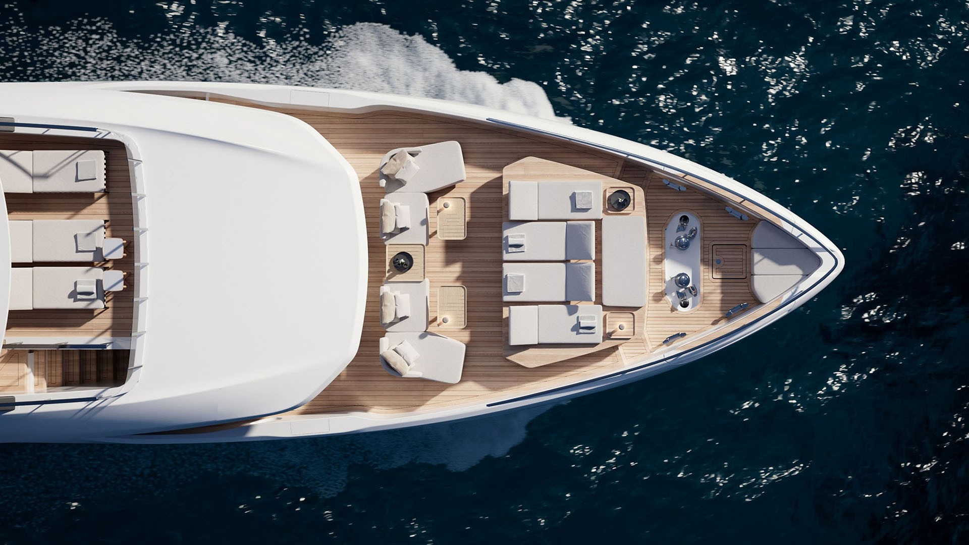 Looking straight down on the bow from above, teak decking laid between two seating groups and a sunpad, with the superstructure filling the left of the frame