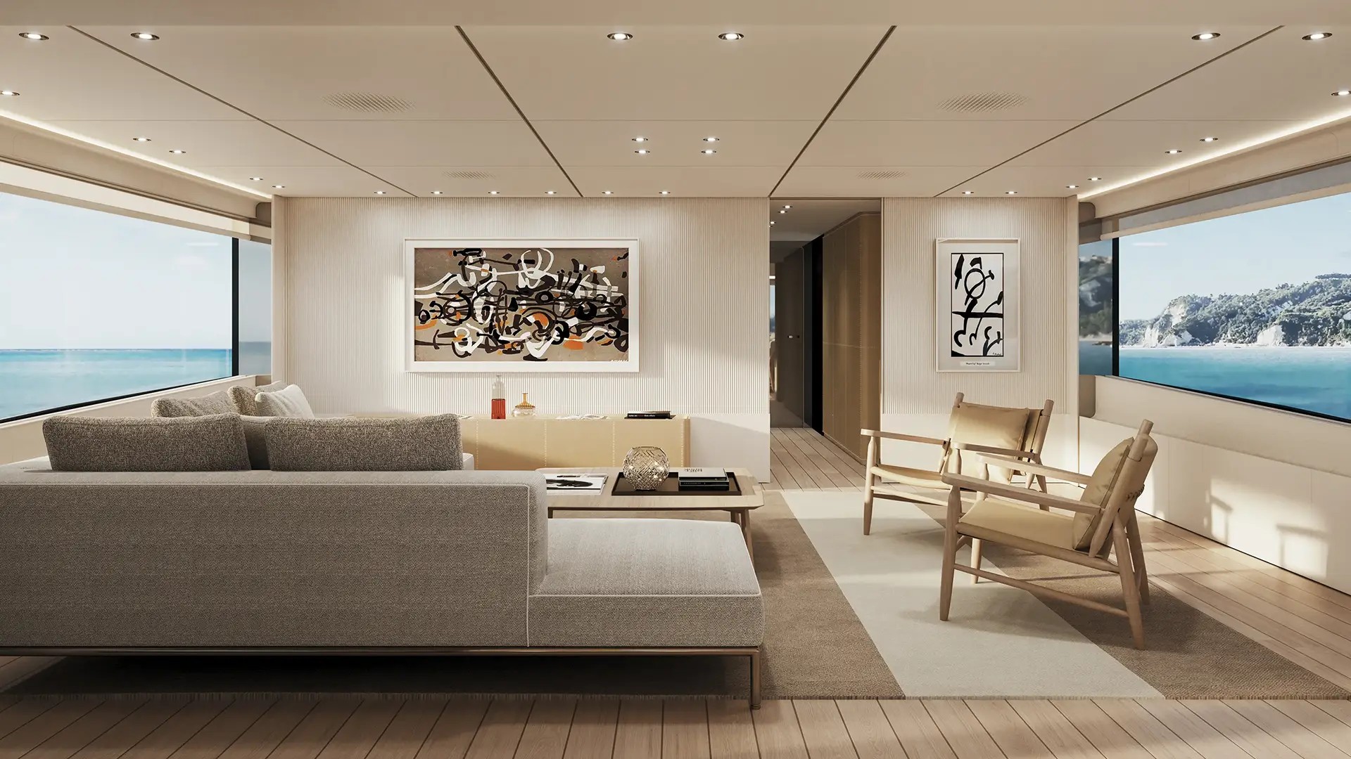 The saloon looking forward, a long grey sofa and day bed on a pale rug facing two wooden armchairs, with a framed abstract painting on the bulkhead and full-height windows to both sides