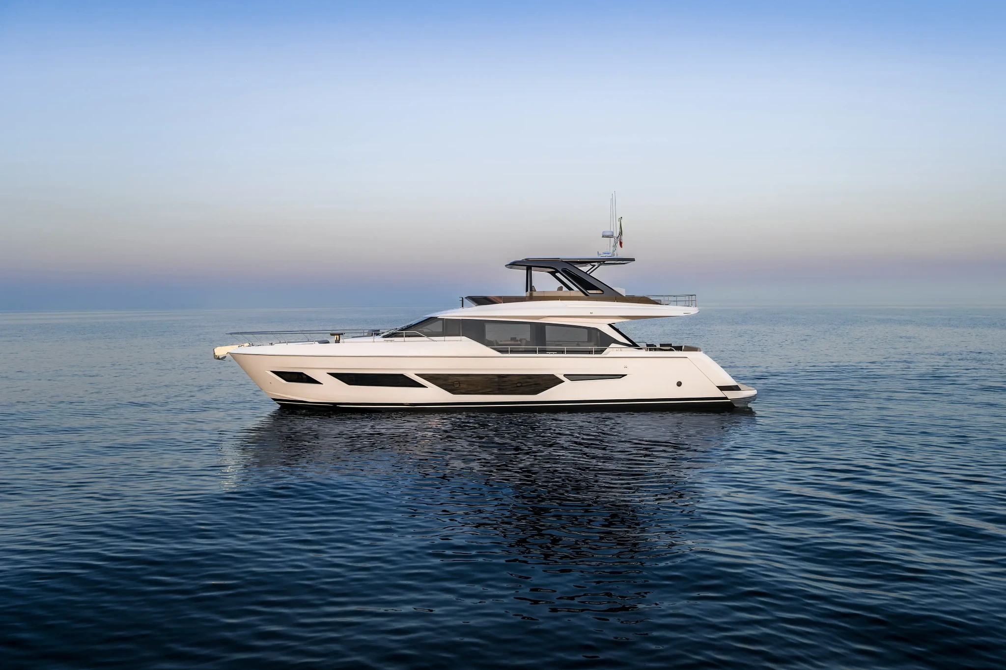The 720 lying motionless on a mirror-flat sea in pale evening light, seen exactly side on with her reflection below her