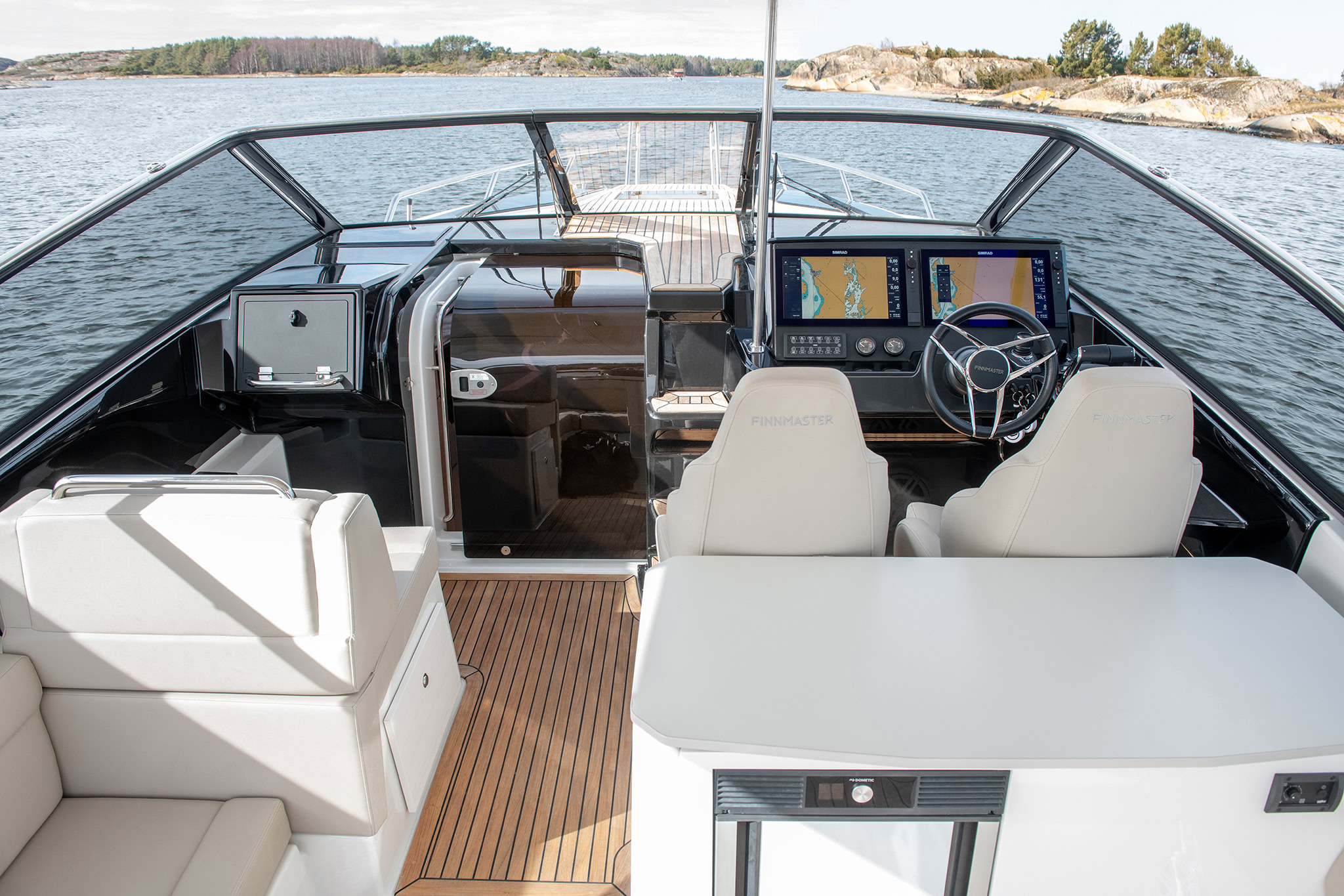 The cockpit looking forward to the helm, with a table and white seating