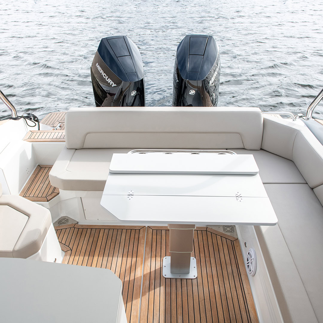 A folding table on the teak aft deck, the outboards visible astern