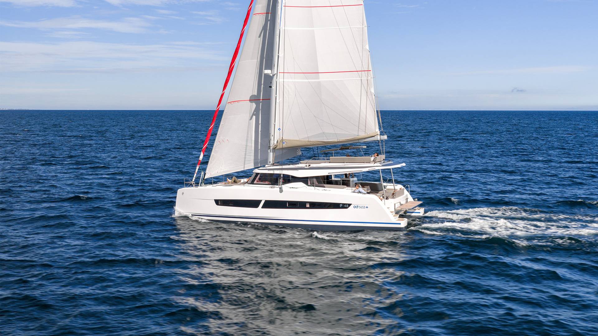 The catamaran sailing in profile under main and headsail