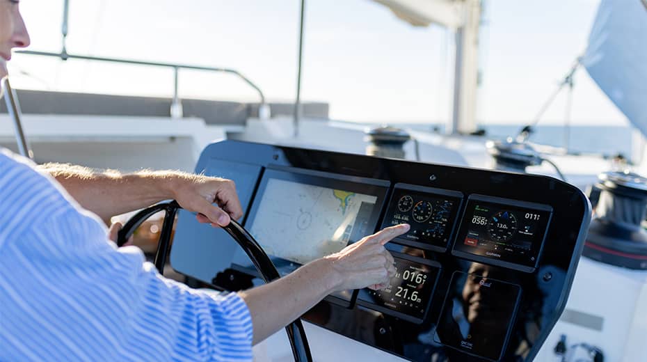 A hand on the wheel at the helm station beside its displays