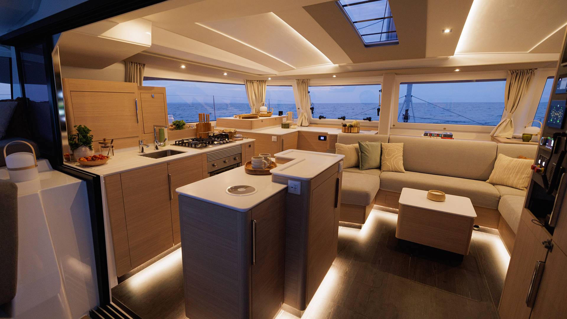 The saloon and galley lit from within at dusk, the doors open to the cockpit