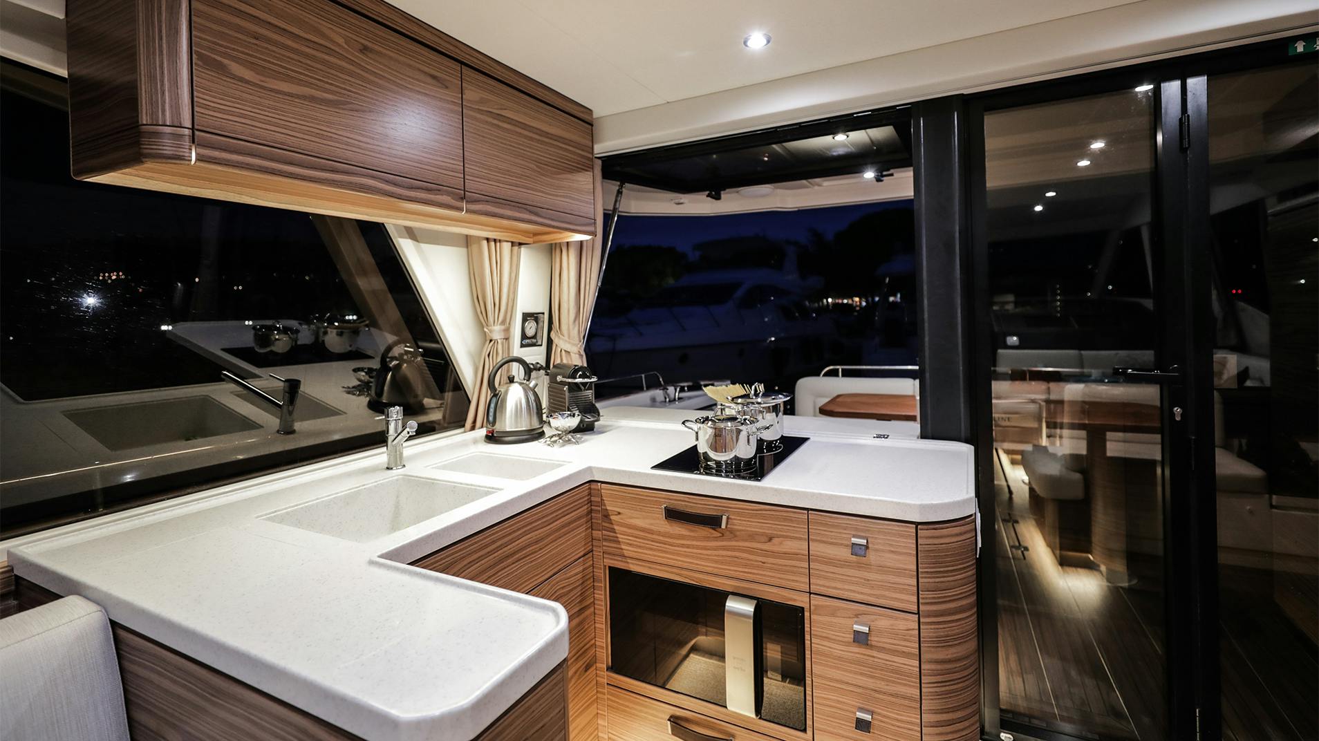 The galley, with a sink, a hob and wood cabinets lit at night