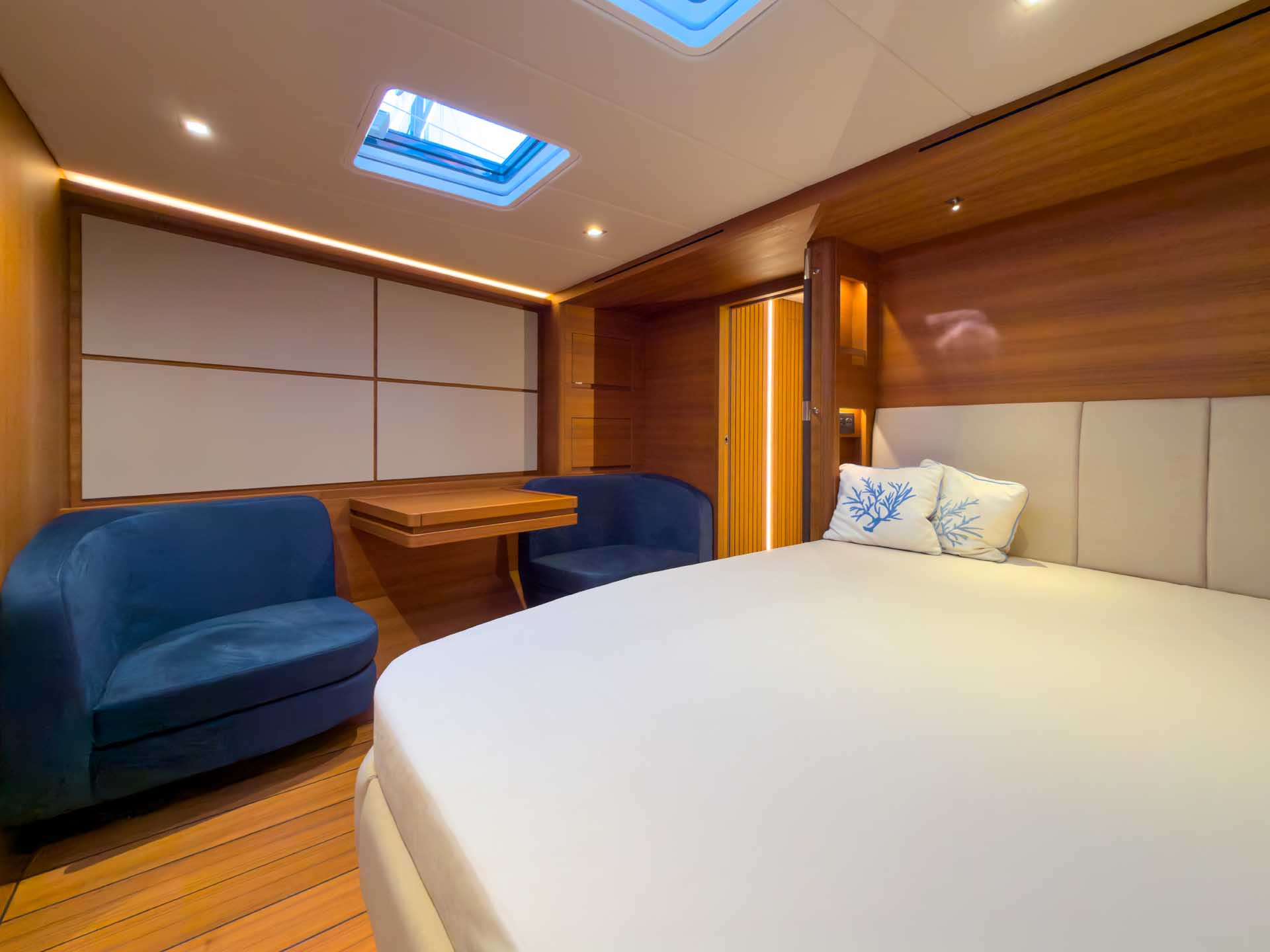 A double cabin with a tub chair, a desk and a deck hatch above the berth