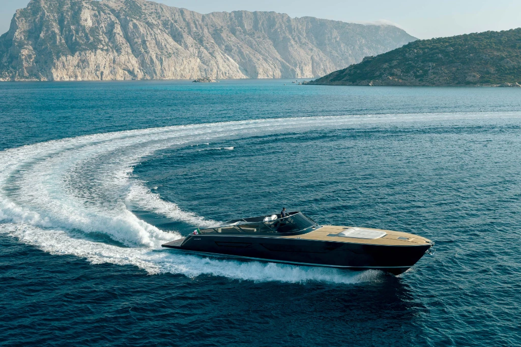 The Itama 70 running hard through a turn, carving a curved wake off a rocky coast