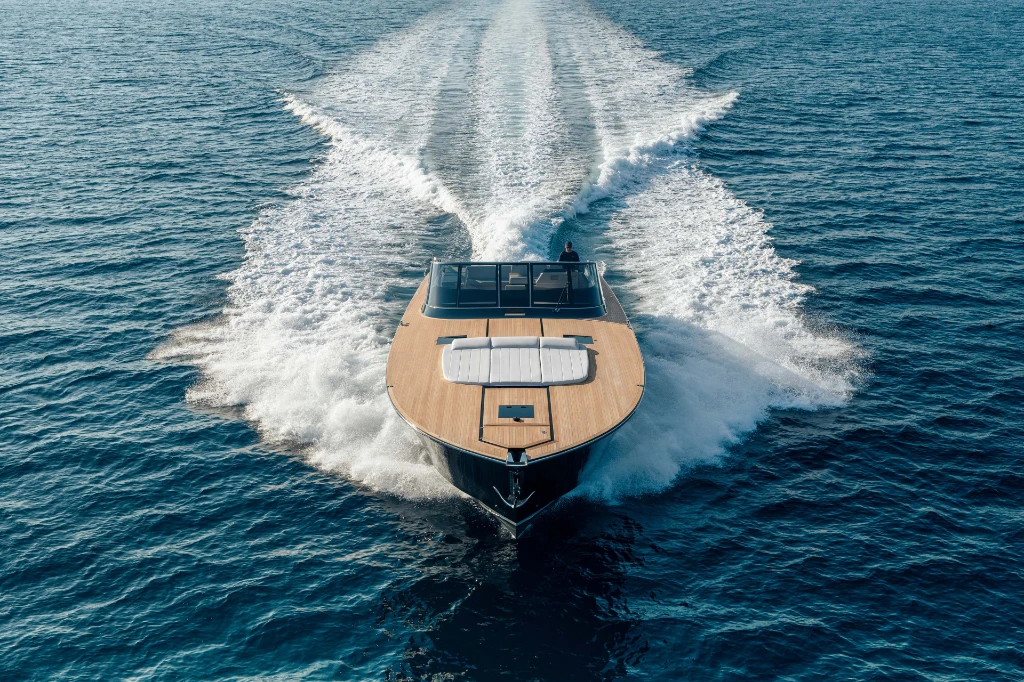 The Itama 70 head-on at speed, showing the bow sun pad set flush into the teak foredeck
