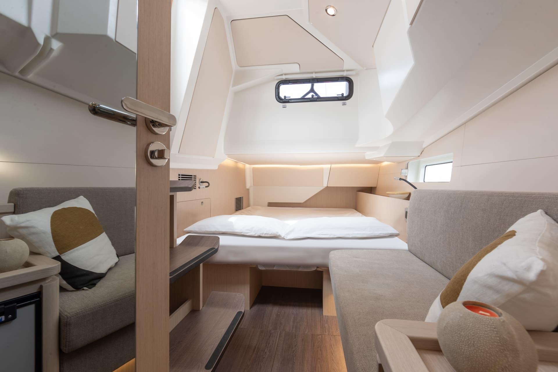 A guest cabin with a berth under a hull window and a seat beside it