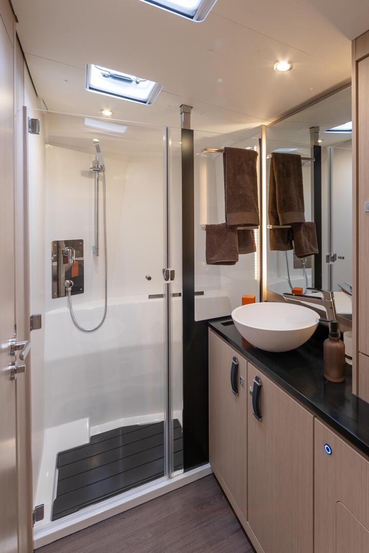 A bathroom with a basin on a dark worktop and a separate shower stall