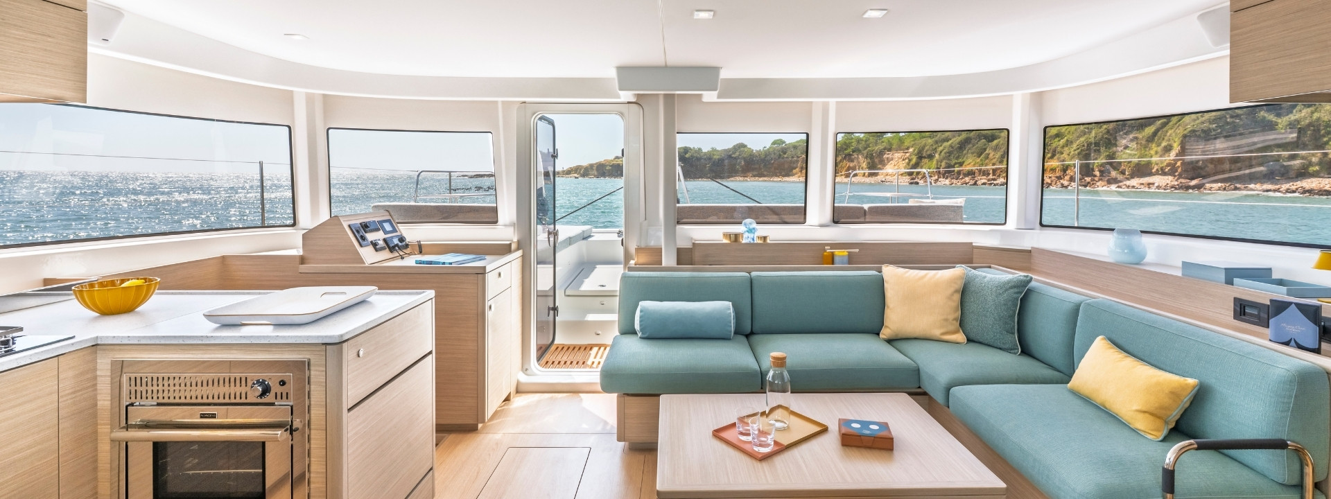The saloon, with the galley to one side and a sea-green L-shaped sofa and table beneath wraparound windows
