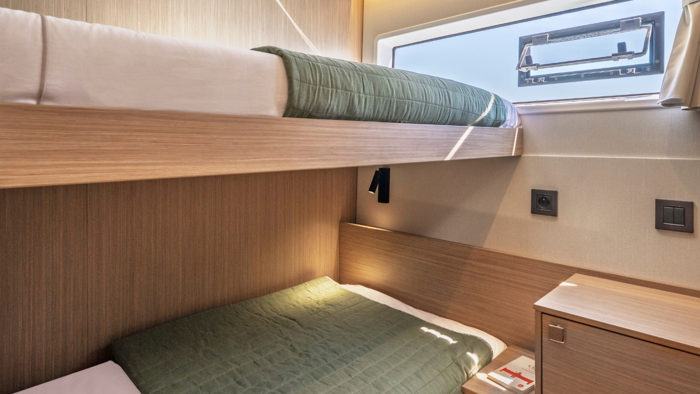A cabin fitted with two single berths, one above the other, beside a hull window