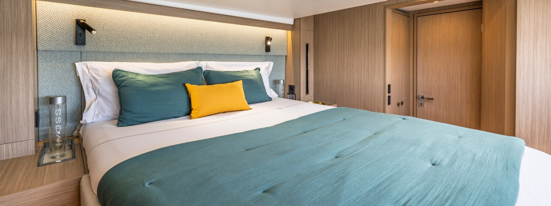 A double berth made up in sea-green linen against an oak bulkhead