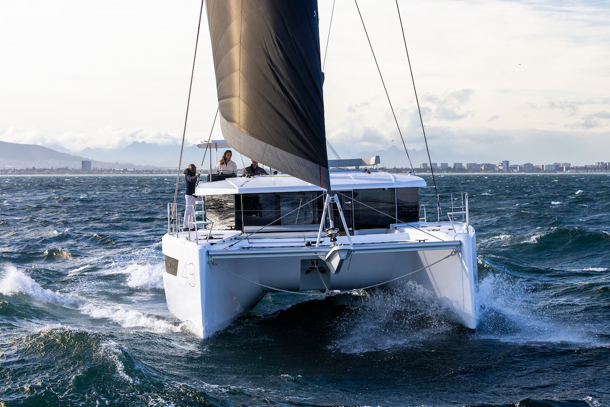 The Leopard 43 sailing on a breeze, heeled slightly, with mountains astern