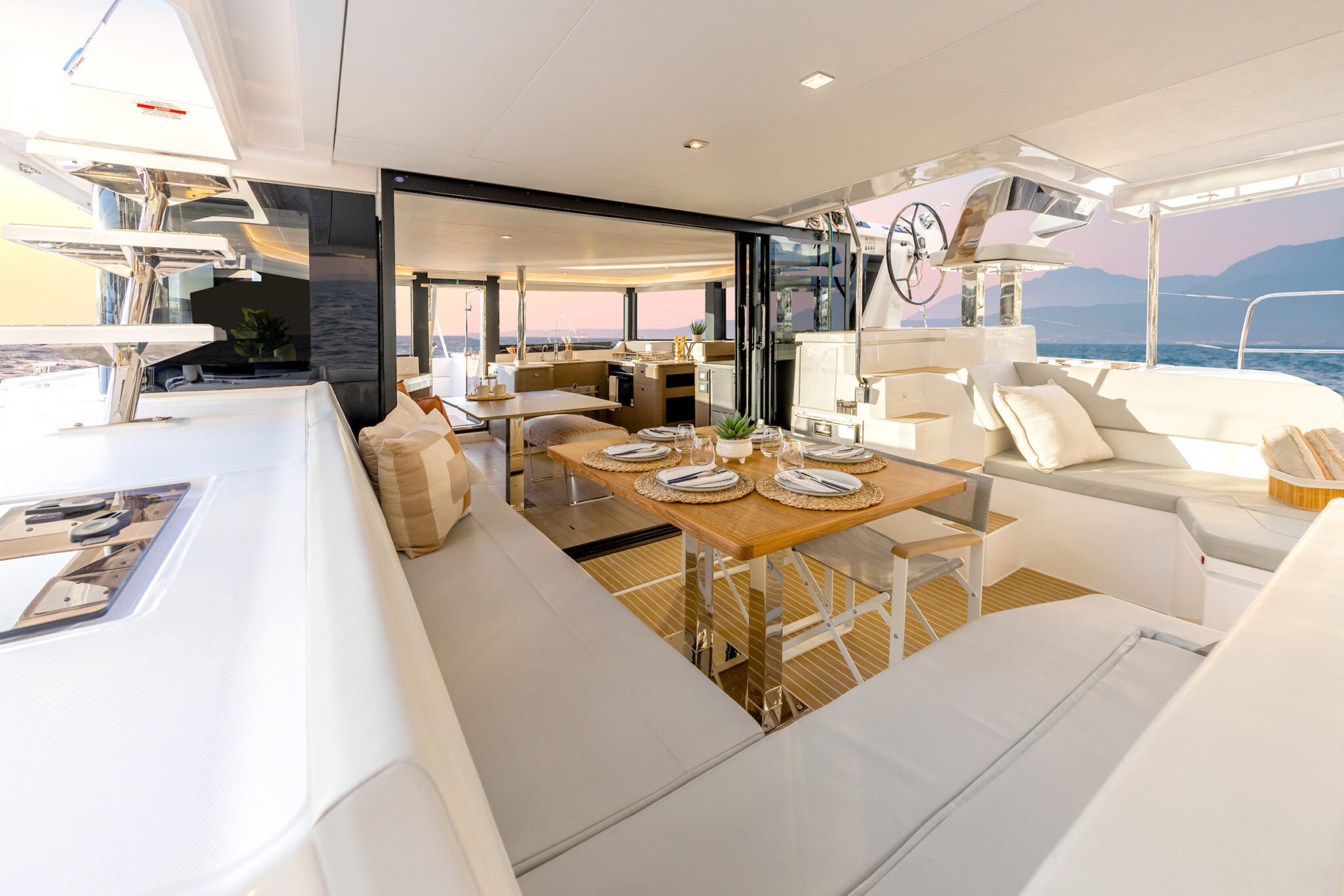 The aft cockpit, with a dining table and the glass companionway doors open to the saloon