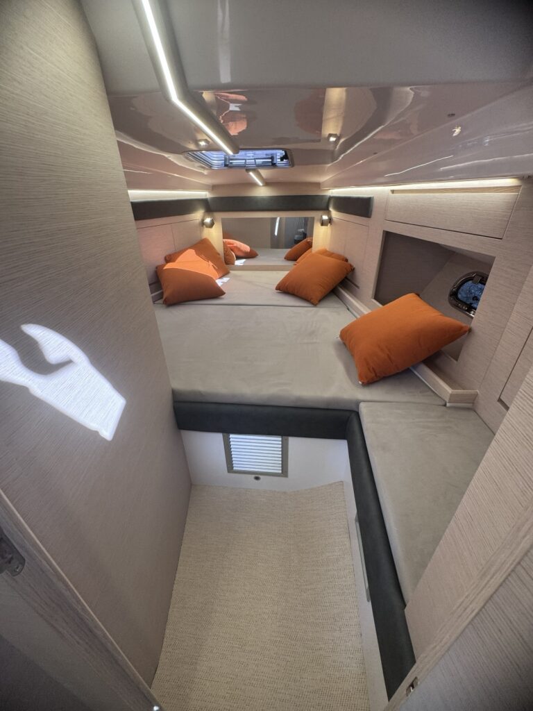 A cabin below with a double berth and orange cushions, lit from a hatch