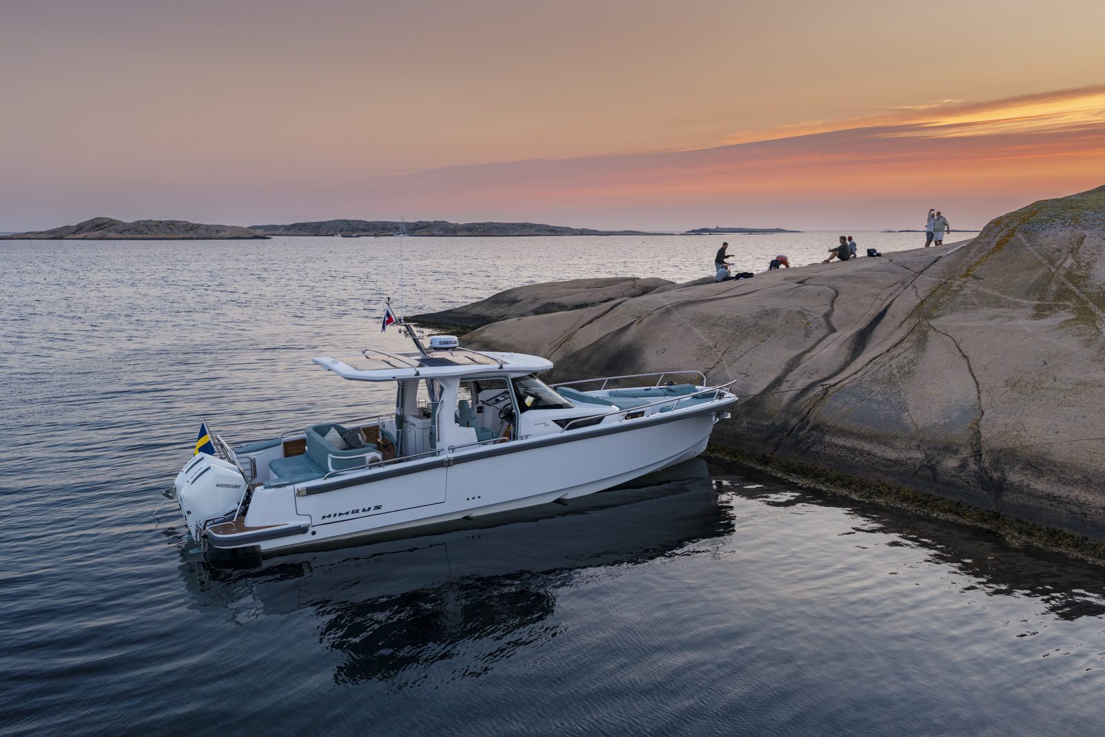 The 35 close in against granite rocks at dusk, with people on the shore