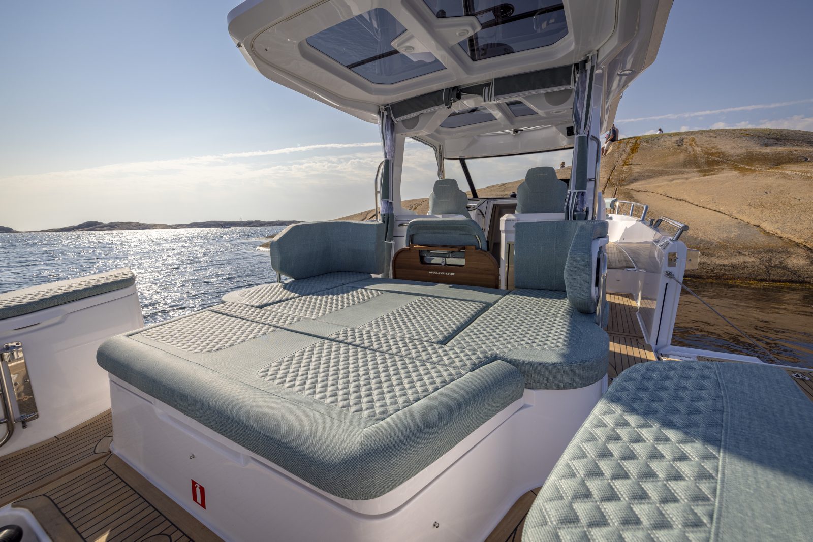 The aft deck under the T-top, with the sunbed made up and the sea beyond
