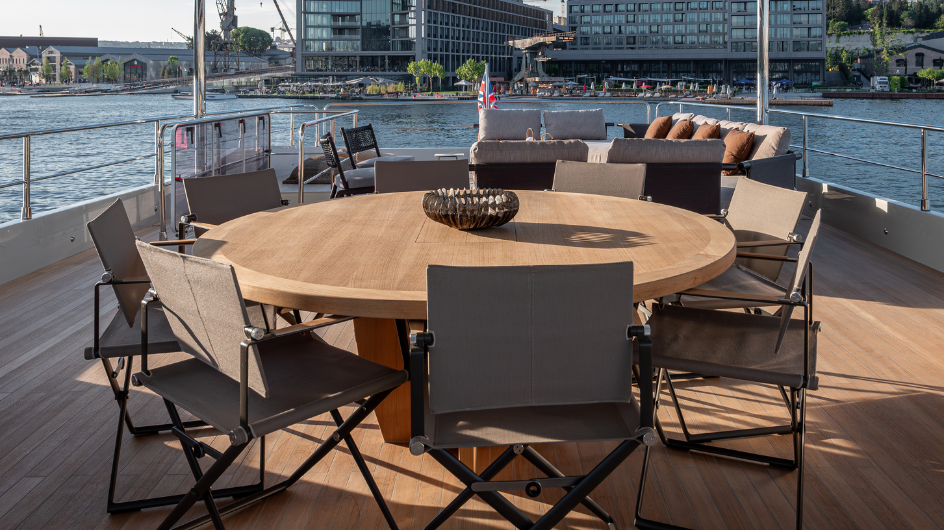 The aft deck laid for dinner, with a round table and folding chairs under the overhang