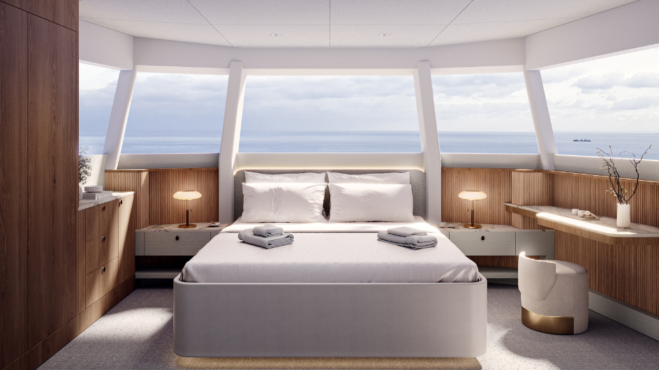 A cabin with a double berth between two bedside tables, under windows that wrap around the bow