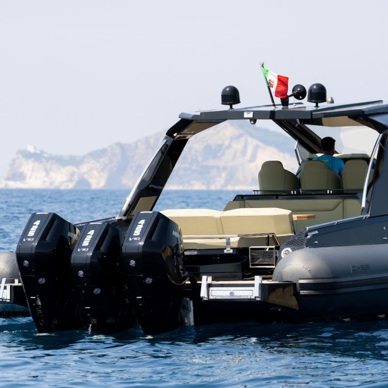 The stern at anchor, with three black outboards beneath the T-top