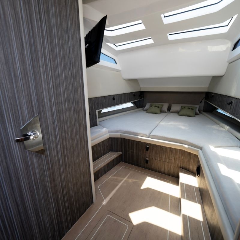 A cabin with a double berth under skylights, lined in dark grey wood