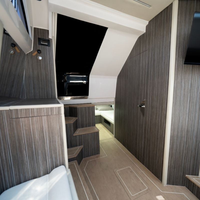 The companionway below deck, panelled in dark grey wood, leading to the cabins