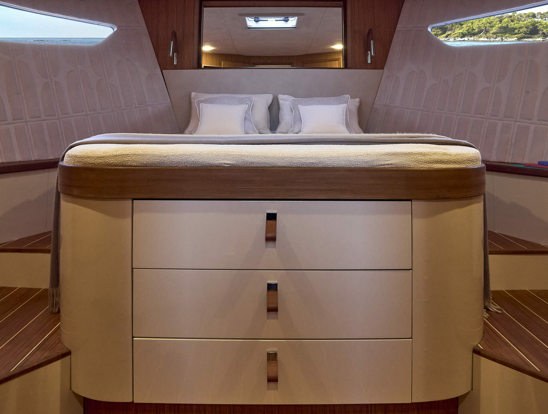 A cabin with a double berth and a chest of drawers in pale wood