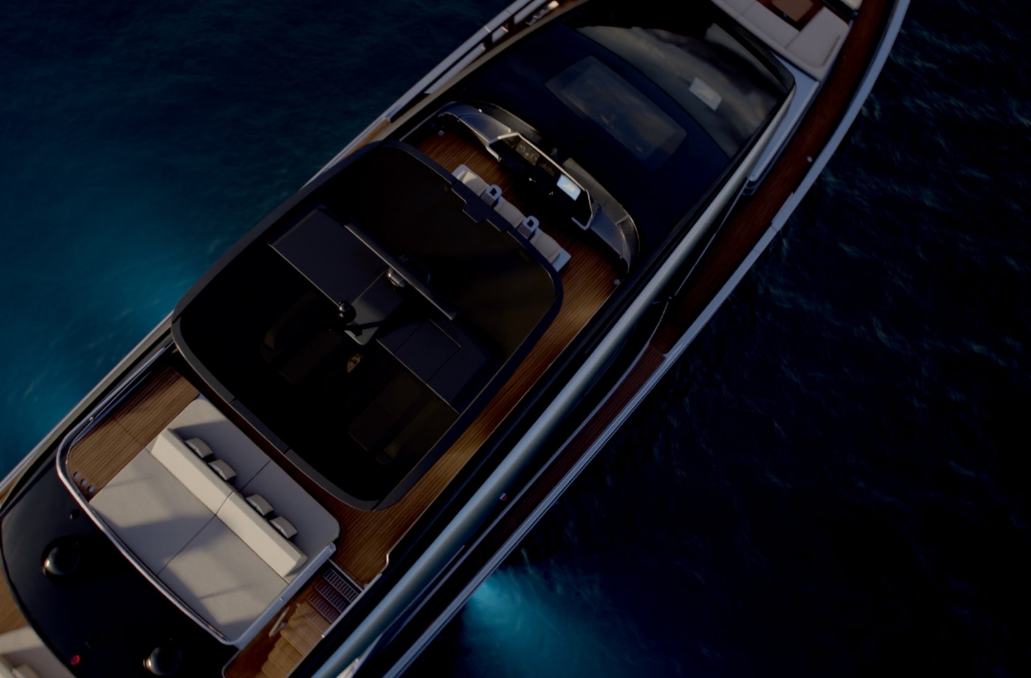 Looking down on the GTX90's decks from above, the dark glazed roof over the saloon, teak side decks and a cockpit sunpad, with turquoise water either side