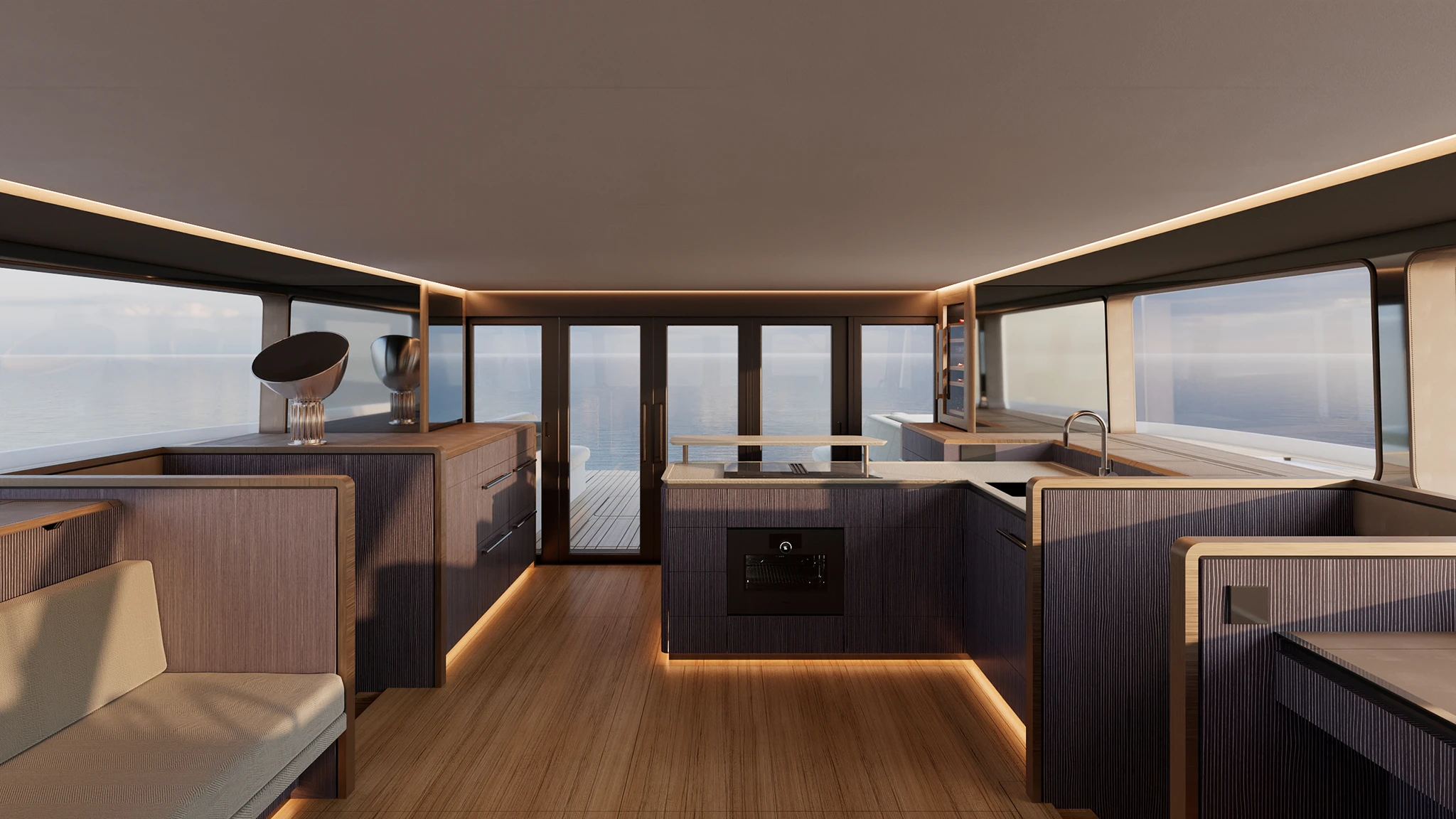 The saloon and galley, in dark ribbed joinery with lit plinths and a wood sole, an induction hob, oven and sink, and glazing all round to the sea