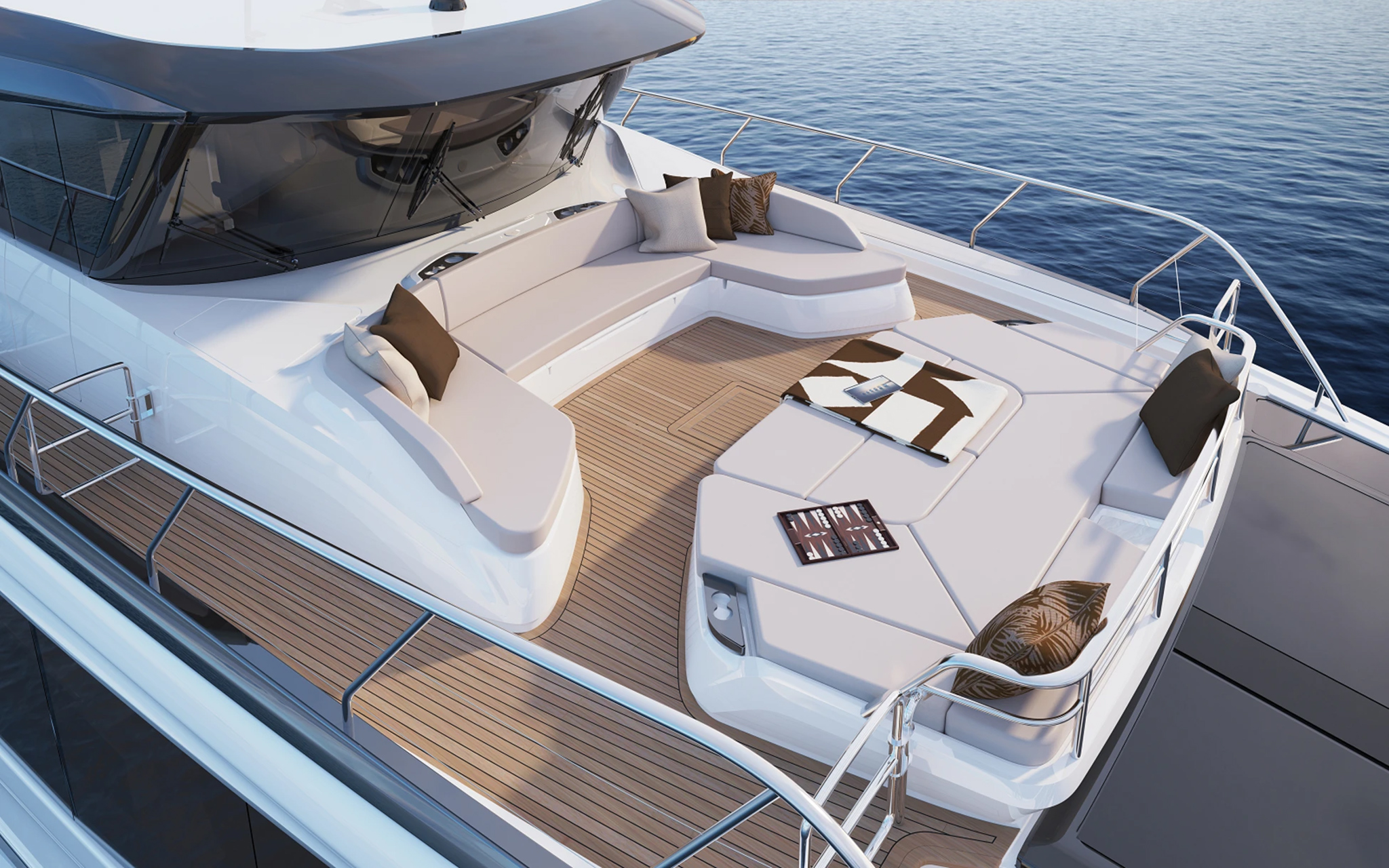 Looking down on the foredeck, a curved seating group around the raised windscreen with a large sunpad beyond it, a backgammon board set out on the cushions