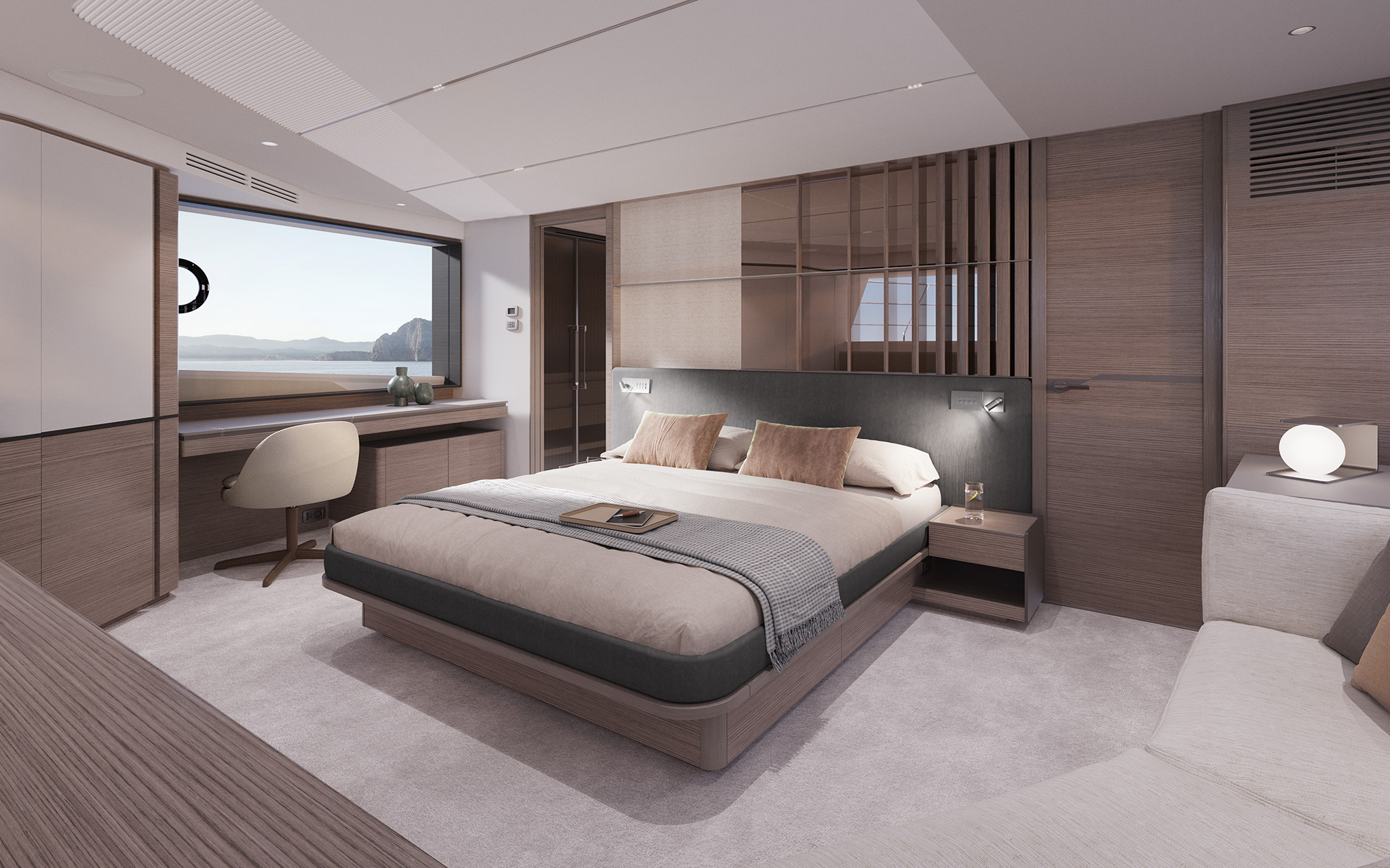 A double cabin running the full width of the hull, the bed against a dark padded headboard with a slatted timber screen above, a desk and chair under a large hull window to one side