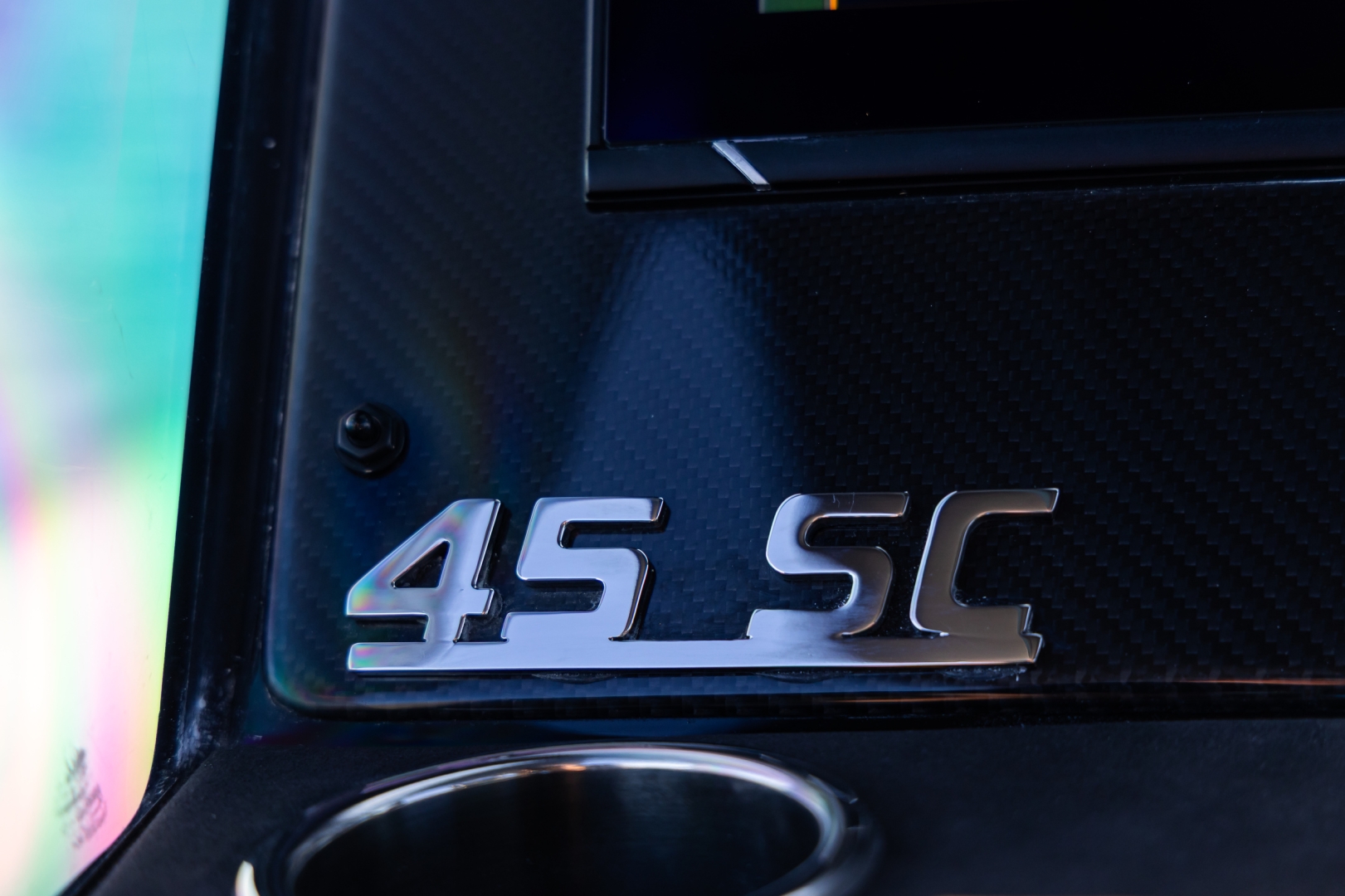 A close view of the carbon dashboard, with the chromed 45 SC badge beside a cup holder