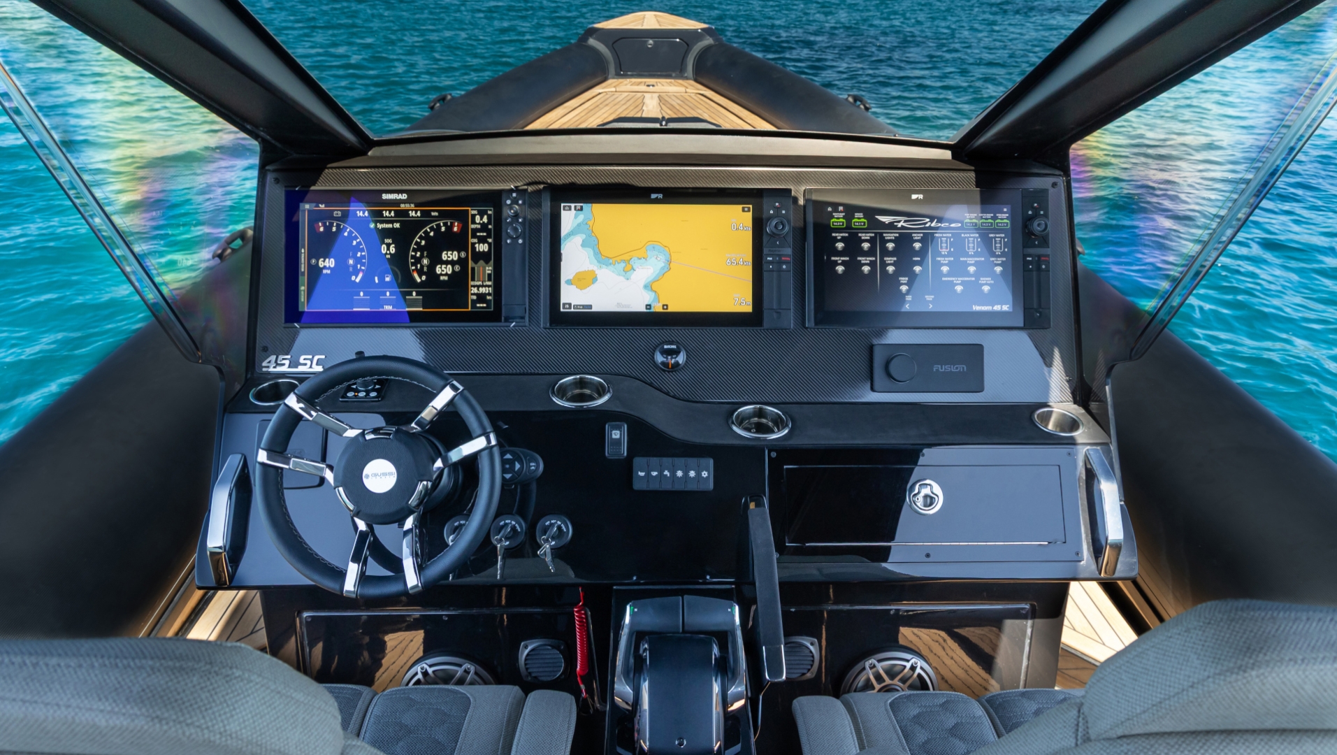 The helm from behind the seats: three screens across a carbon dash, a small wheel and the throttle between the bolsters