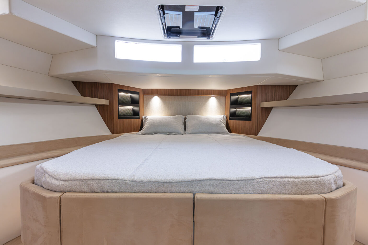 A cabin with a double berth against the hull side and reading lights above