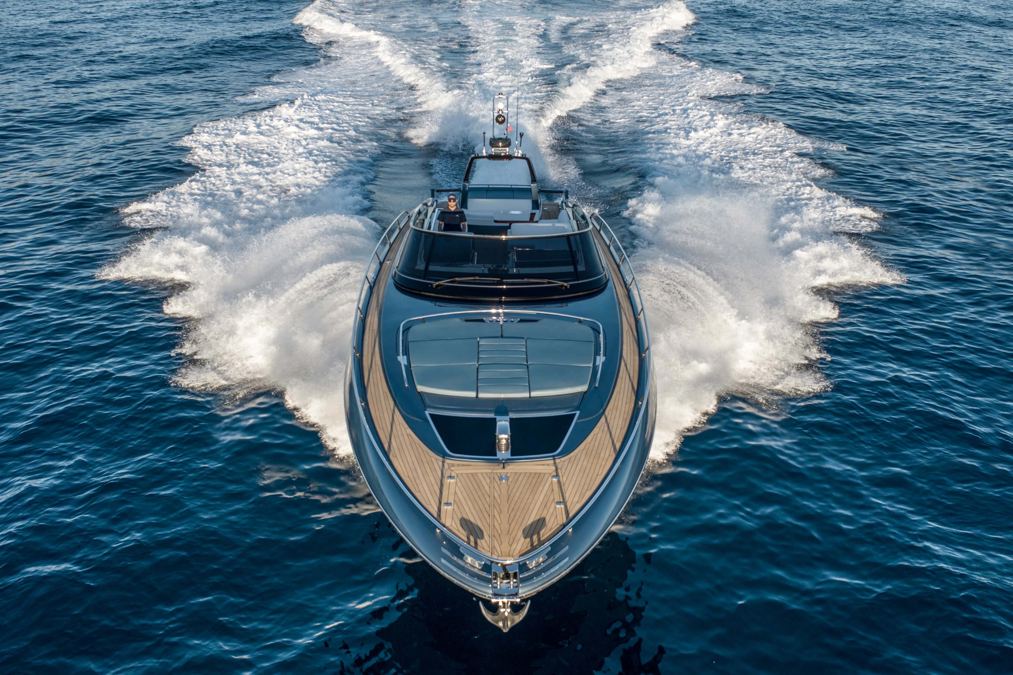 The Riva 56 Rivale Super seen head on at speed from above, spray fanning either side of her bow and the foredeck sunpad and helm visible under the open hardtop