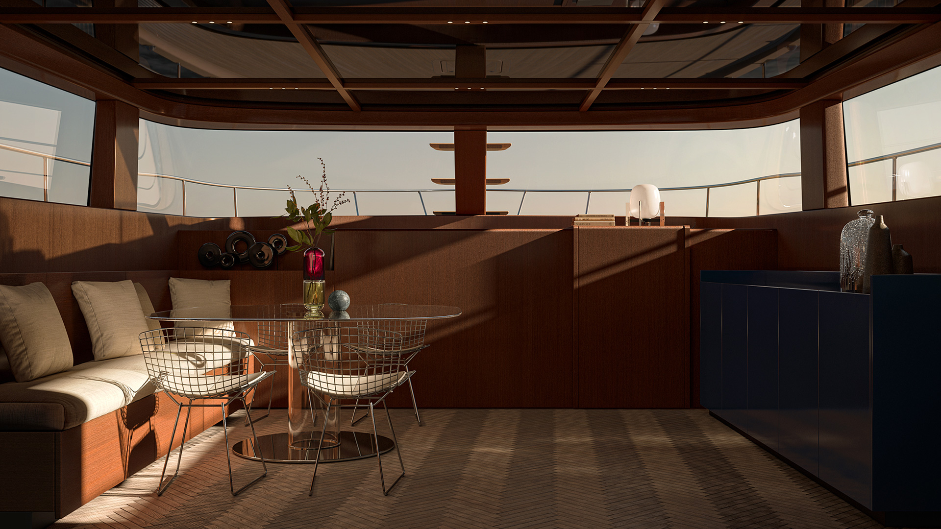 A dining area under an overhang, with a table and chairs against open glazing