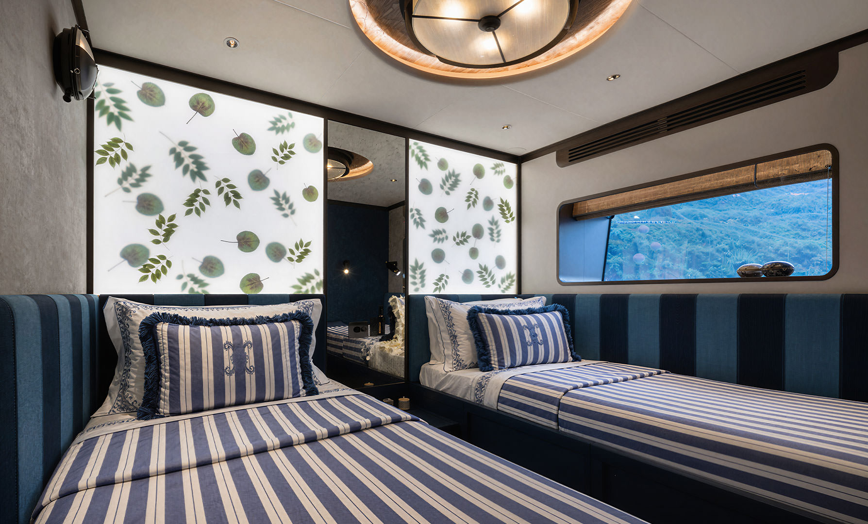 A twin cabin with striped bedding, a porthole and patterned wall panels