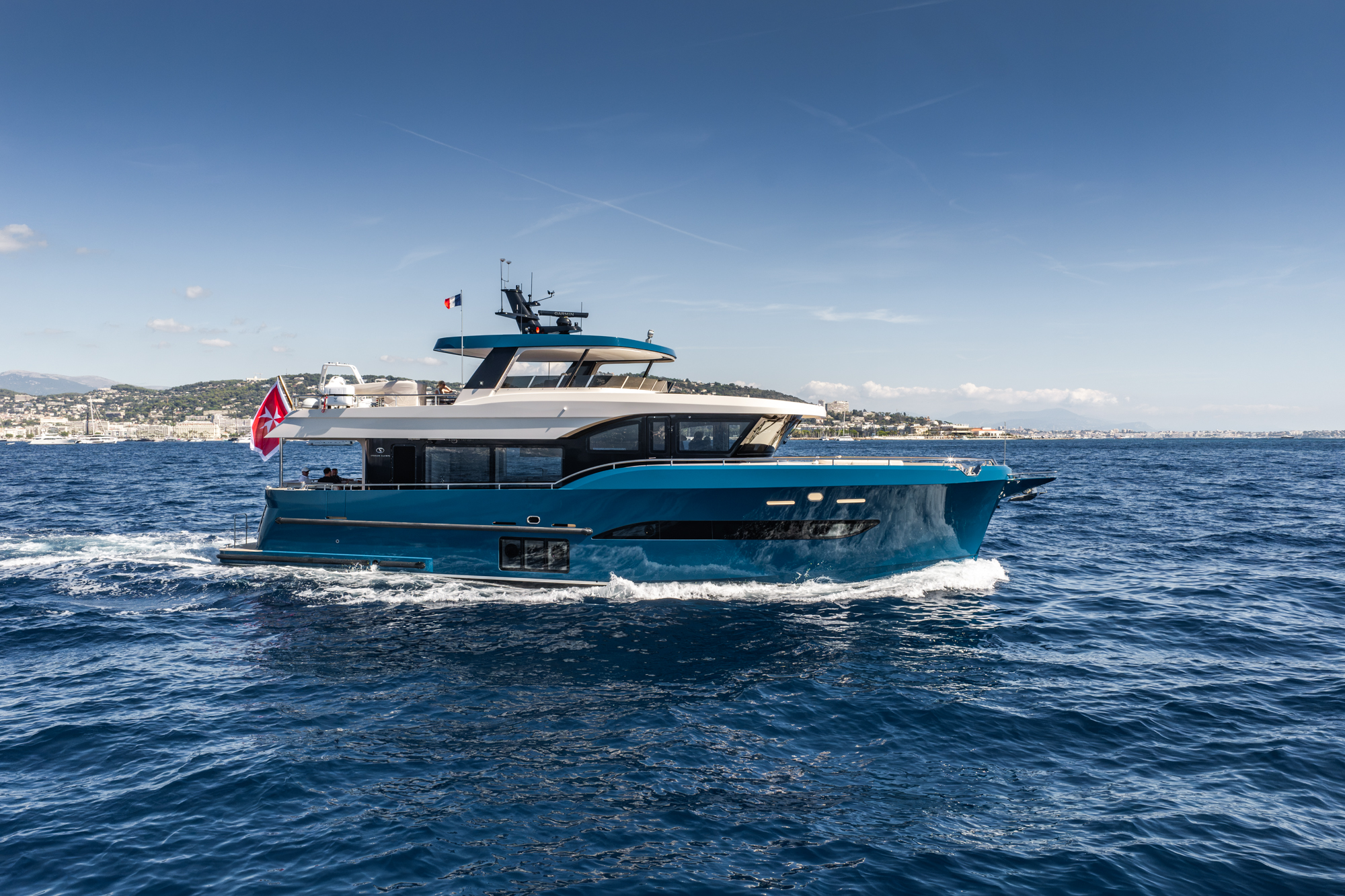 The 67 running past a coastline, showing the enclosed flybridge