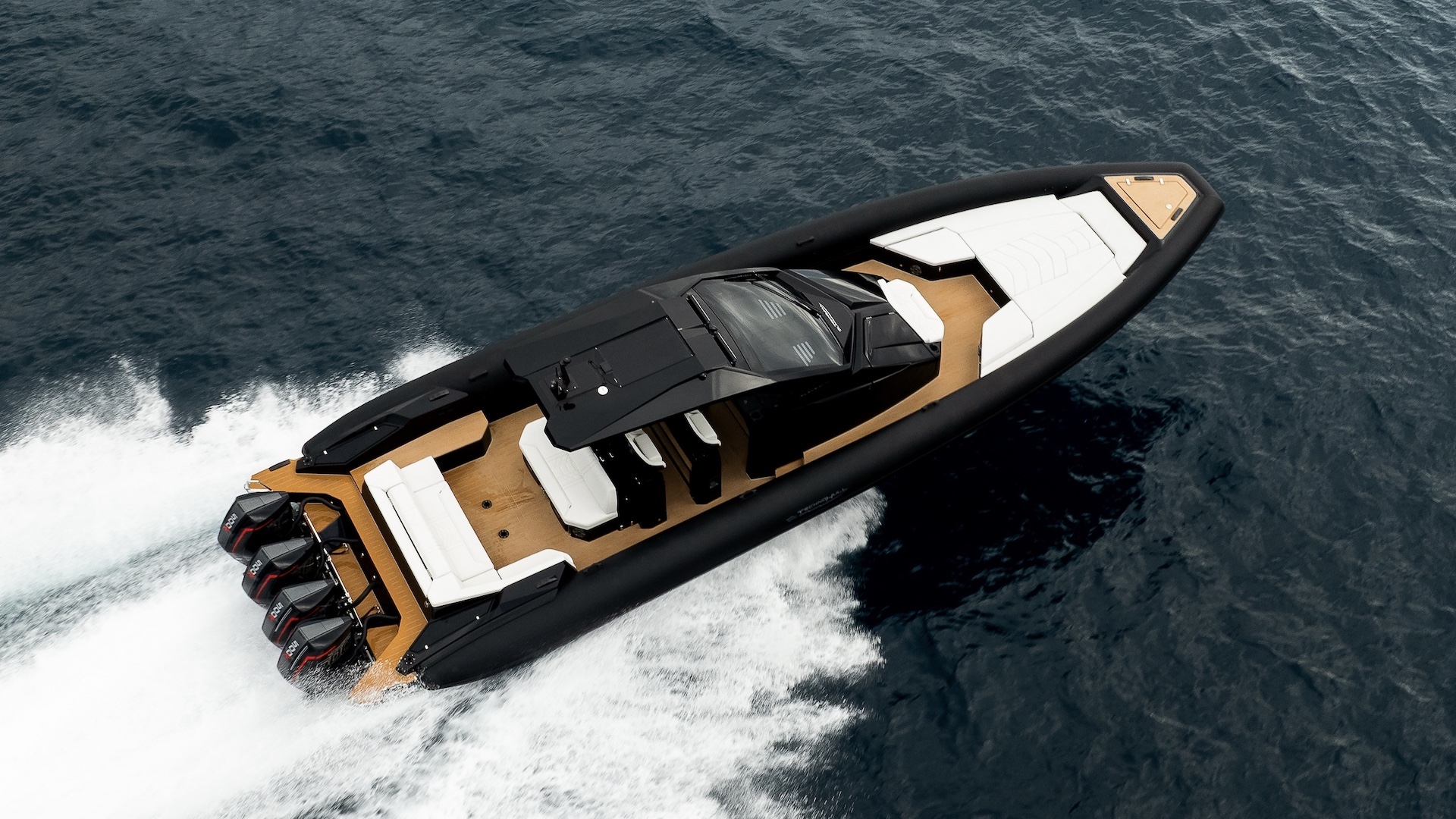Seen from above at speed: the bow sunpad, the central console under the hardtop and the aft sunbed on a teak-coloured deck
