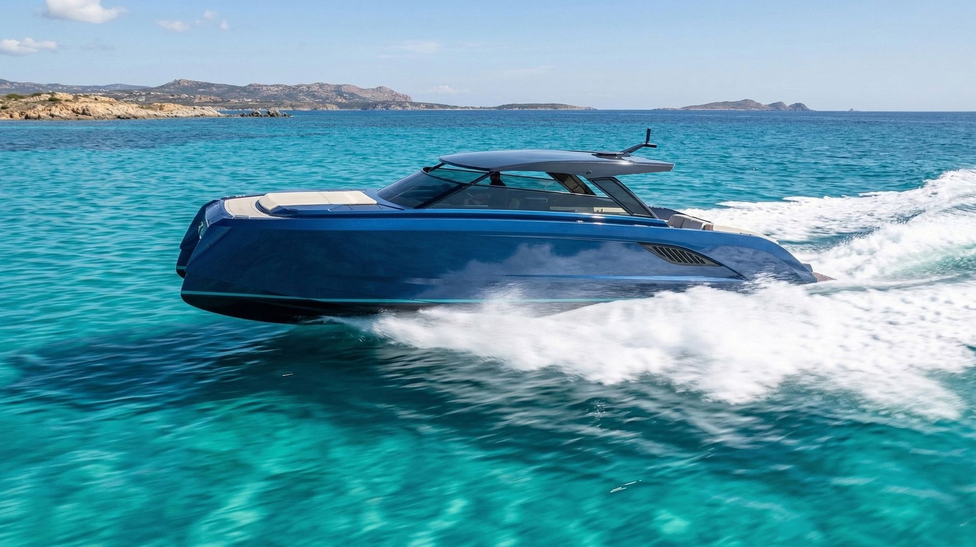 The Vybe 43 running at speed seen from the side, its navy hull throwing a wake across turquoise water, with a low hard top over the helm and an island shore behind
