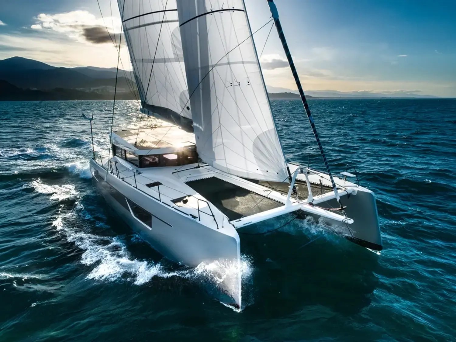 The catamaran sailing with a mountain coast behind