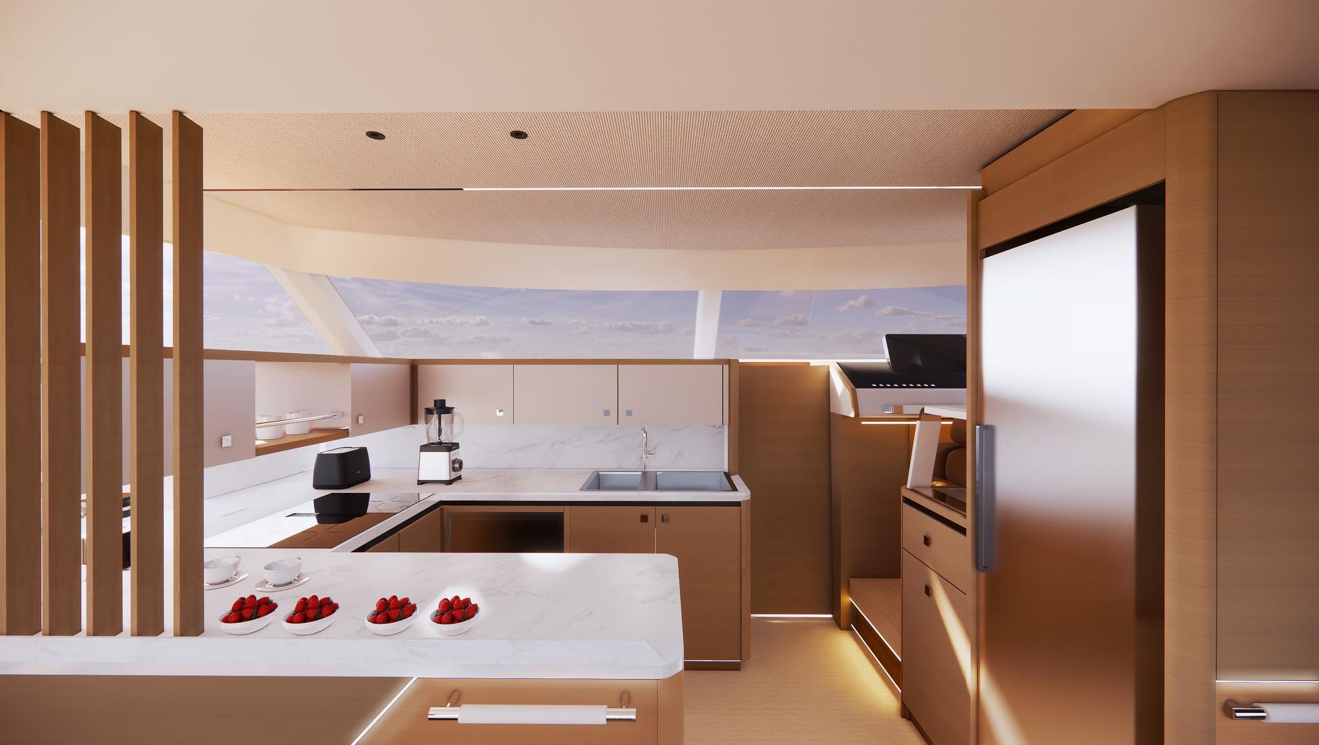 The galley, finished in pale wood with white stone worktops, a sink and an induction hob under a long hull window