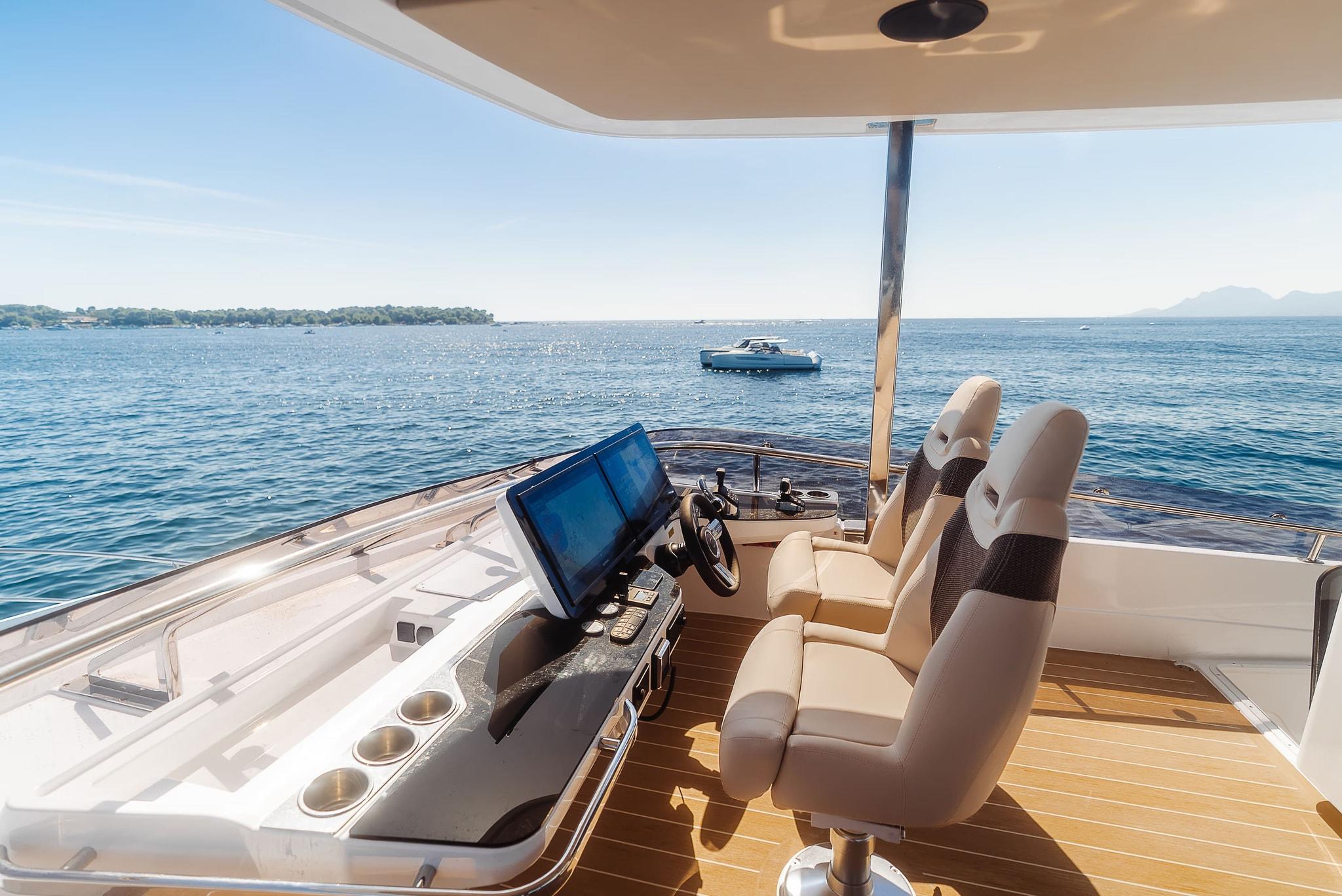 The rooftop helm, two seats at a console with a wide screen and a small wheel, looking out over the water