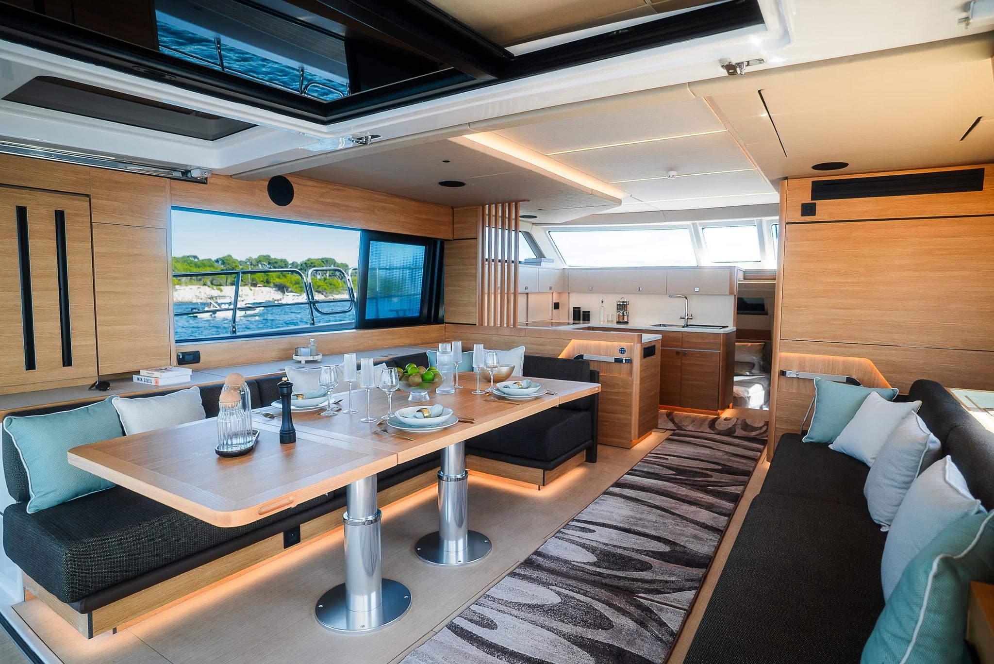 The saloon looking forward, a long dining table between facing settees with the galley beyond