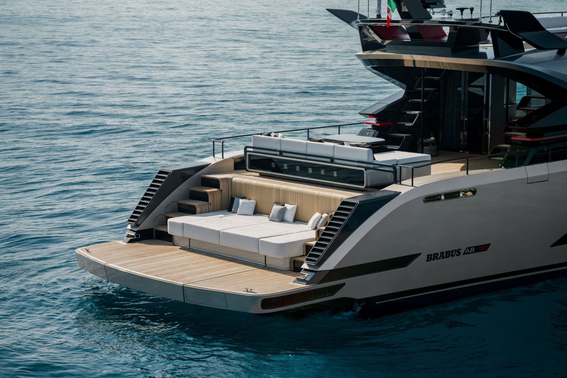The stern of the BRABUS AB110 from above, teak bathing platform, a double sunpad and a bar lettered BRABUS, carbon stairs on both sides